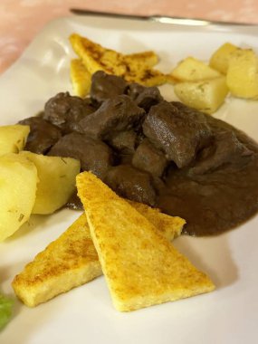 Patatesli leziz biftek güveci ve beyaz tabakta ızgara polenta..