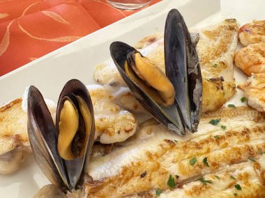 Beyaz tabakta midye, karides ve balık ızgara deniz ürünleri tabağı..