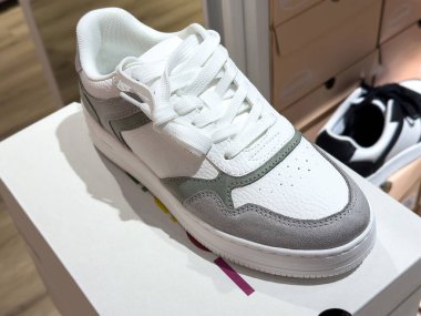 Ayakkabı mağazasında şık beyaz ve gri spor ayakkabılar sergileniyor..