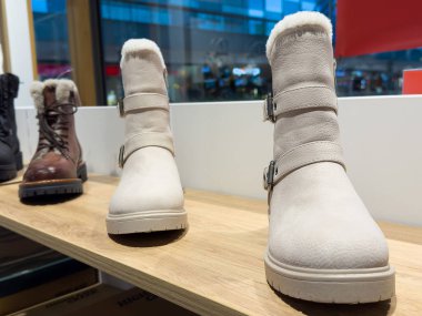 Mağazada kürklü bej renkli kış botları sergileniyor..