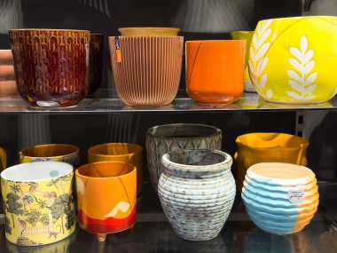 Renkli seramik ekiciler bir ev dekoratöründe parlak güneş ışığında sergileniyor.