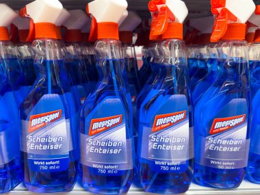 Blue de-icer bottles on store shelf with orange spray nozzles. clipart