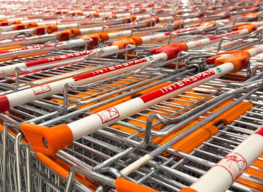 Süpermarkette turuncu saplı sıra sıra alışveriş arabaları.