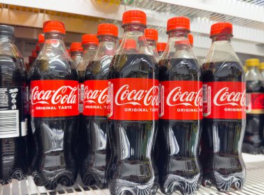 Marka ve ambalaj tasarımı gösteren Coca-Cola şişeleri mağaza rafında.
