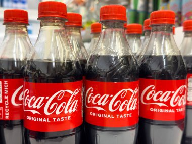 Coca-Cola şişeleri mağazada kırmızı etiketler ve orijinal marka ile sergileniyor..