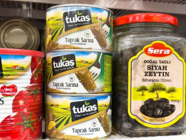 Kutular dolusu tukas yaprak sarma ve rafta bir kavanoz sera siyah zeytin.