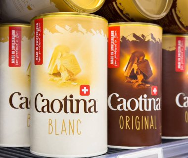 Caotina Blanc ve orijinal İsviçre çikolatalı içecek kutuları rafta..