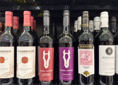 Rafta çeşitli kırmızı şarap şişeleri var..