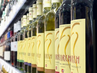 Assorted wine bottles on supermarket shelf in austria displaying diverse varietals. clipart