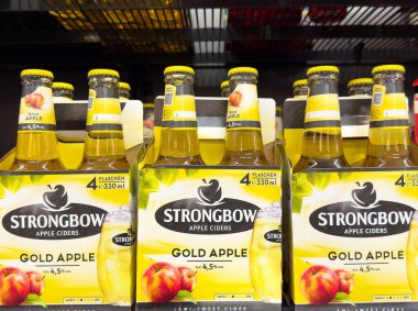 Güçlü altın elma şıraları canlı ambalajlı vitrinde sergileniyor.