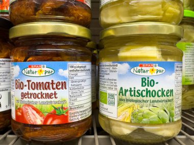 Rafta organik kurutulmuş domates ve enginar kavanozları var..