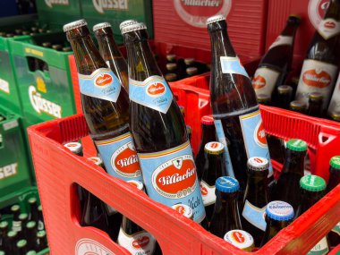 Mağaza rafındaki kırmızı sandıkta çeşitli bira şişeleri..