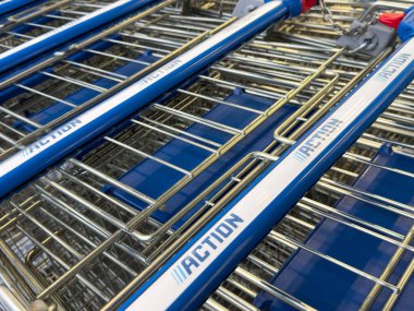 Mağazanın otoparkında mavi saplı metal market arabaları..