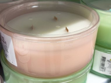 Raftaki pembe cam kabın içinde üç fitil kokulu mum..