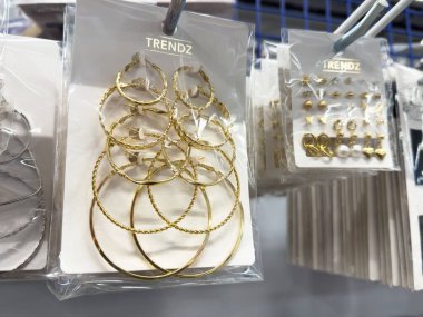 Askıda trendz altın ve gümüş halka ve küpe gösterimi.