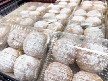 Süpermarket raflarında sergilenen plastik kaplarda pudralanmış çörekler..