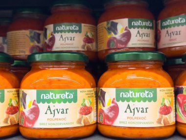 Ekranda Ajvar kavanozları: keskin kırmızı biber ve patlıcan yayılmış.