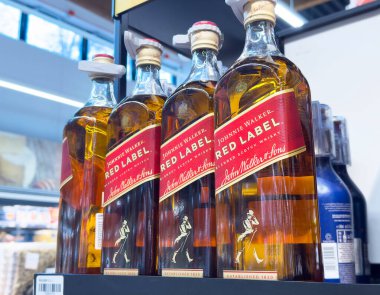 Johnnie Walker kırmızı etiket şişeleri rafta sergileniyor.