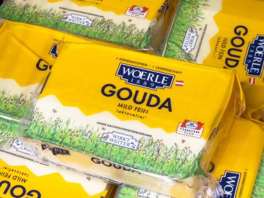 Parlak sarı ambalajlı Gouda peyniri blokları ve manzaralı çayır tasarımı..