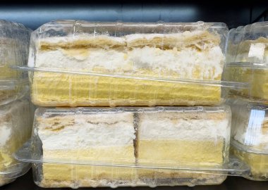 Açık plastik kaplarda sergilenen katmanlı kremalı kekler..