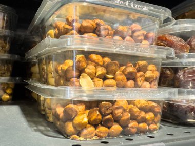 Plastic containers filled with fresh hazelnuts stacked on market shelf. clipart