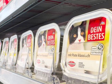 Mağaza rafındaki kedi maması ürünlerinde siyah beyaz kedi resmi içeren ambalajlar.