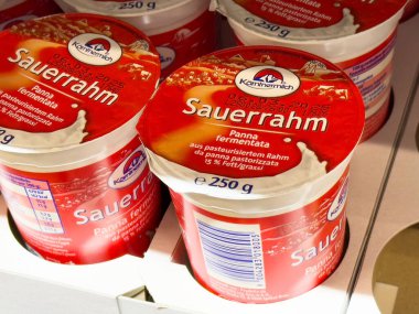 German sour cream product packaging in refrigerated display. clipart