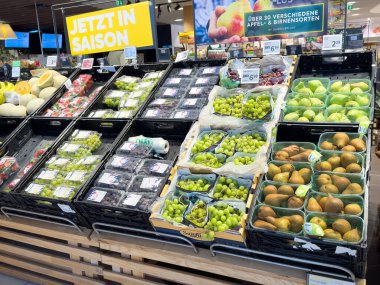 Avrupa süpermarketinde mevsimlik meyveler sergilenmektedir: üzümler, elmalar, armutlar.