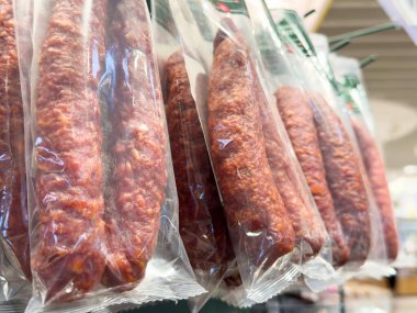 Market koridorunda paketlenmiş sosisler sergileniyor.