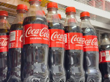 Vitrinde kırmızı etiketli Coca-Cola şişeleri.