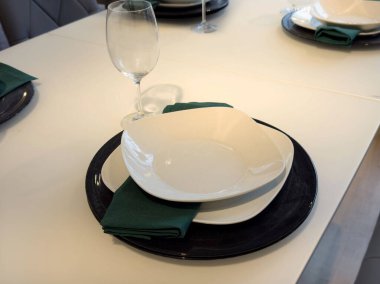 Kare tabaklar ve siyah şarjlı yeşil peçeteler ile zarif bir yemek düzeni..