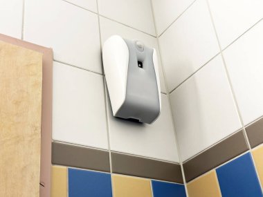 Duvara monte edilmiş otomatik oda spreyi fayanslı banyo köşesinde..