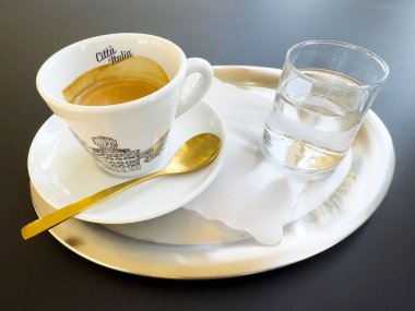 Altın kaşıkla gümüş tepside kahve fincanı ve bir bardak su..