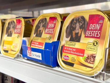 Dachshund ve Almanca metin etiketli köpek maması rafında.