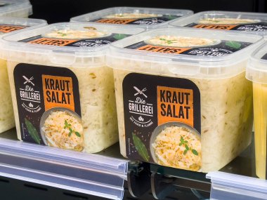 Dondurulmuş koridorda ambalajlı Alman salatası kutuları sergileniyor..
