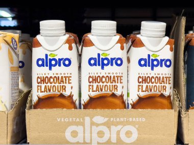 Silky smooth plant-based chocolate flavored alpro drink cartons on shelf. clipart