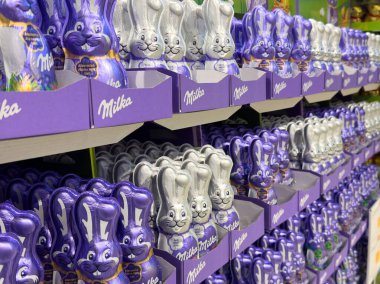 Market raflarında mor ambalajlı çikolatalı paskalya tavşanlarının görüntüsü.
