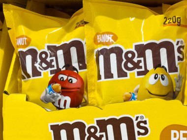 Renkli m & m 'nin fıstık paketleri süpermarket koridorunda sergileniyor.