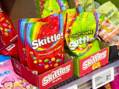 Market koridorunda renkli meyveler ve ekşi şeker sergisi.