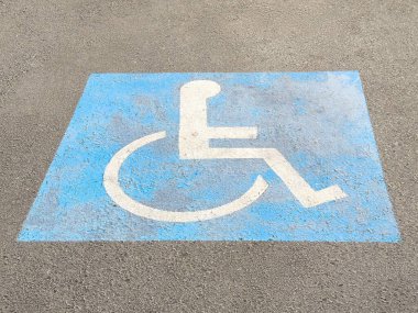 Asfalt yüzeyine boyanmış erişilebilir park alanı sembolü engelliler için ayrılmış alanı belirtiyor kapsayıcılık kavramını destekliyor