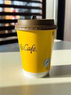 McCafe kahve fincanı, güneş ışığıyla aydınlanan parlak sarı tasarım, sıcak bir içecek deneyimi, kahve kültürü konsepti,