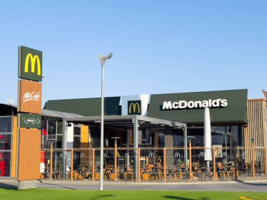 Fast food restoranının dış görünüşü McDonald 's marka, modern mimari, açık hava oturma alanı ve canlı tabela, yemek deneyimi konseptini gösteriyor.