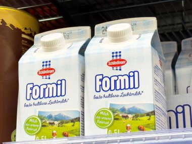 Bir süpermarkette sergilenen süt kutuları kırsal manzaralı Formil markasını gösteriyor, süt tazeliğini ve kalitesini vurguluyor, sağlıklı beslenme kavramını vurguluyor.