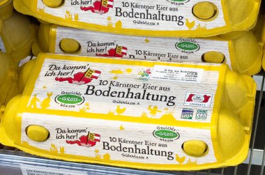 Canlı sarı bir karton içinde taze organik yumurtalar süpermarket rafında sergileniyor, gıda üretiminde kalite ve sürdürülebilirlik gösteriliyor, sağlıklı beslenme konsepti