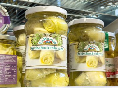 Süpermarket rafında sergilenen cam kavanozlardaki enginar kalpler, canlı renkler ve çekici ambalajlar, mutfak yemekleri ve sağlıklı yeme konsepti için mükemmel.