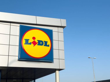Lidl süpermarket önü, parlak mavi gökyüzü, modern mimari, ve canlı logo, uygun fiyatlı alışveriş deneyimi, perakende konsepti