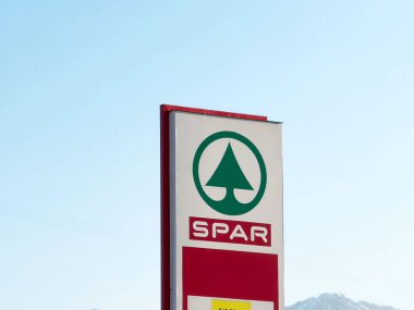 Açık mavi gökyüzü ve dağ zeminine karşı spor süpermarketi işareti, marka kimliği ve perakende varlığı sergileniyor, açık hava reklamcılığı konsepti