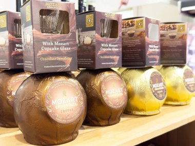 Ahşap bir rafta sergilenen eşsiz kapkek cam ambalajı çeşitli aromalar ve tasarımlar sergiliyor, tatlı sunumundaki yaratıcılığı ve yeniliği vurguluyor