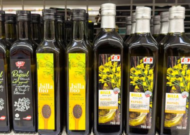 Bir süpermarketin rafında sergilenen zeytinyağı şişeleri çeşitli markalar ve ambalajlar sunuyor, sağlıklı aşçılık ve aşçılık kullanımlarını temsil ediyor, sağlıklı beslenme kavramını