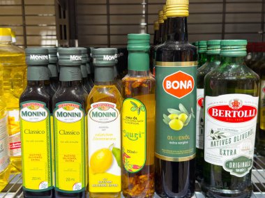 Çeşitli zeytinyağı şişeleri ve aromalı yağlar bir marketin rafında çeşitli marka ve türleri sergilenerek sağlıklı pişirme konsepti için sergileniyor.